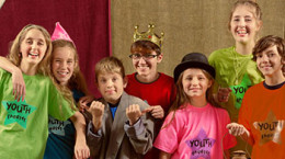 Cheerful group of child actors stand together and smile at the camera